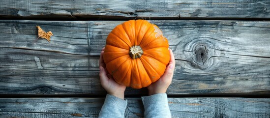 Poster - A pumpkin held by a child on a wooden board, viewed from above with space for text or images, symbolizing the autumn harvest season.