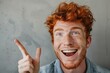 © Igor - Portrait of happy redhead man with freckles with open mouth smiling and gesturing up with index finger