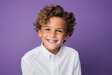 Portrait of a cute happy little boy with curly hair over purple background