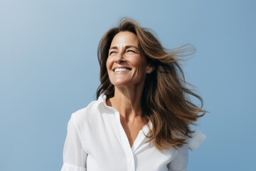 Canvas Print - Portrait of a happy mature woman smiling at the camera over blue background