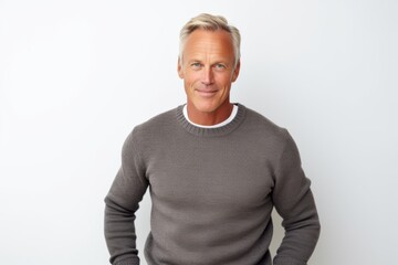 Poster - Portrait of handsome mature man looking at camera and smiling while standing against white background