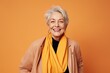 © Stocknterias - Cheerful senior woman in stylish clothes posing over orange background.