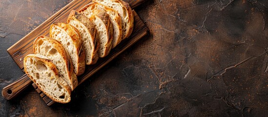 Poster - Fresh slices of homemade baguette on a dark wooden board with whole grain and a wooden background in a top view featuring a copy space image