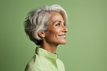 Wall Mural - Portrait of smiling senior woman looking away over green background. Copy space.