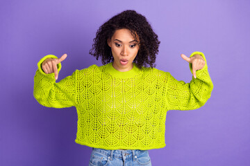 Wall Mural - Photo of charming youth girl in bright yellow knitted sweater indicating fingers down shocked isolated on purple color background