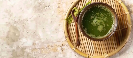 Poster - Top view of a brown Cup filled with Matcha green tea on a bamboo plate with a spoon against a light background with copy space image