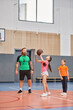 © LIGHTFIELD STUDIOS - A man, showing basketball techniques, plays with children in a gym filled with energy and excitement.