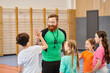 © LIGHTFIELD STUDIOS - A bearded man stands confidently in front of a group of children, engaging them in a lively classroom setting.