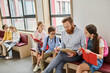 © LIGHTFIELD STUDIOS - A man, the teacher, sits before a group of kids in a bright and lively classroom, animatedly reading a book to captivate their imaginations.
