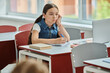 © LIGHTFIELD STUDIOS - A young girl sits at a desk, with bored face expression in school