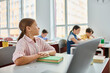 © LIGHTFIELD STUDIOS - A girl immersed in her work, sits at a desk with a laptop open in front of her, focused and engaged in the digital world.