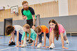 © LIGHTFIELD STUDIOS - A diverse group of kids, coached by a man, performing push-ups on a gym floor with determination and focus.