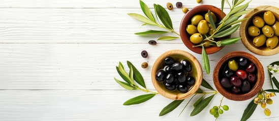 Poster - Varieties of olives displayed in bowls with olive oil leaves and black olives on a white wooden backdrop Copy space image available for text with a Mediterranean and vegan food theme