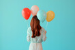© Pacharee - Back view of woman holding balloons for celebration or birthday party on color background.