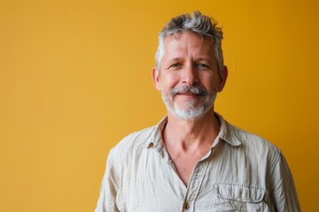 Wall Mural - Portrait of a happy man in his 50s wearing a simple cotton shirt in solid color backdrop