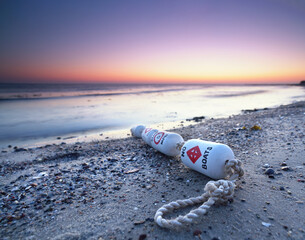 Poster - romantic sunset at the beach with a buoy in the sand