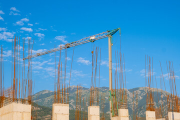 Construction site with tower crane against mountain landscape and blue sky