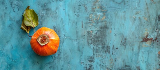 Poster - A ripe orange fig persimmon fruit placed on a textured blue background for a flat lay photo Top view perspective with space for text or images. Copy space image. Place for adding text and design