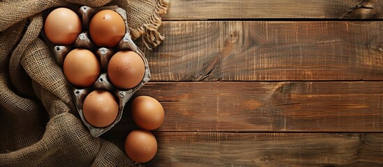 Sticker - Display a rustic wooden background with factory packaged brown raw eggs allowing copy space image