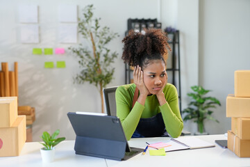 Young female entrepreneur appears overwhelmed and fatigued as she works on her laptop in her office, reflecting on the trials of running a business