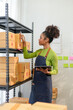 © amnaj - Young african american entrepreneur checks packages in a busy warehouse, managing inventory with a tablet for smooth shipping