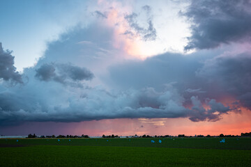 Wall Mural - Beautiful view of a thundery shower, illuminated purple by the setting sun