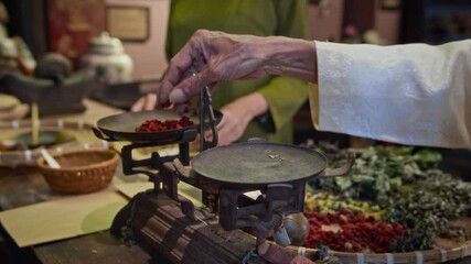 Wall Mural - Cropped shot of hands of unrecognizable Asian healer using scales while preparing herbal mixture at traditional medicine pharmacy