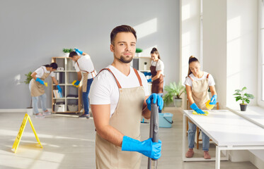 Wall Mural - Male cleaner portrait, happy worker vacuuming, professional janitor service busy cleaning home, office. Young people take care of room, company maintaining washing, dusting, mopping, washing inside 