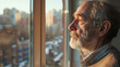 © VK Studio - A contemplative elderly man gazes out of a sunlit window, casting a serene expression as soft sunlight bathes the urban landscape outside.