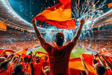 Spanish fan with many more celebrating the victory of his national soccer team in a large soccer stadium, where they have won the European competition