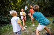 © Mediteraneo - Family of four playing soccer in the park.