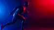 © Alina Tymofieieva - A man in sportswear performs physical exercises on a dark background in neon light. African American man running indoors. Sports concept, active lifestyle.