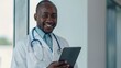 © Daniel - Portrait of smiling doctor with tablet on light grey background