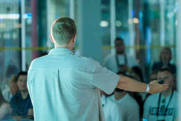 Wall Mural - Male speaker presenting to an attentive audience at a business seminar. Highlighting aspects of engagement, learning, and professional growth.