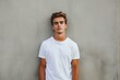 © juliars - Stylish young male model stands confidently in a plain white tee before a concrete backdrop
