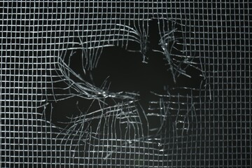 Wall Mural - Torn window screen against black background, closeup