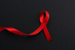 © New Africa - Red awareness ribbon on black background, top view