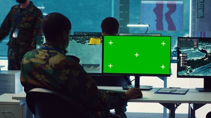 Intelligence analyst reviews ships activity next to an isolated mockup screen, following gps coordinates of vessels anchoring along the coastal ports. Army officer in monitoring room. Camera A.