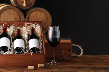 Wall Mural - Wooden boxes, glass, corkscrew and wine bottles on table against dark background. Space for text