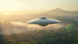 © Pro Hi-Res - A silver flying saucer hovers in the air above a misty, mountainous landscape, with the rising sun casting a warm glow over the scene.