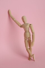 Wall Mural - Wooden human model on pink background. Mini mannequin