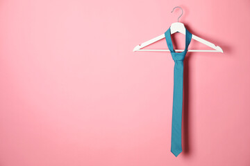 Sticker - Hanger with turquoise tie on pink background. Space for text