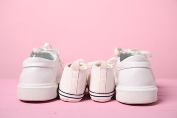 Wall Mural - Big and small sneakers on pink background