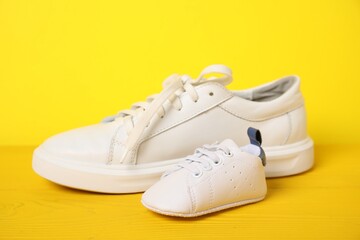 Wall Mural - Big and small sneakers on yellow background