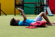 © WavebreakMediaMicro - Smiling biracial schoolgirl lying on her back in school playground reading book, with copy space