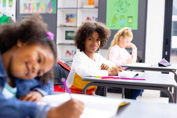 Wall Mural - Happy diverse schoolchildren sitting at desks in school classroom