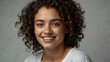 © Adam - A young woman with short curly hair smiling warmly, exuding confidence and natural beauty against a simple, neutral background.