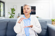 © WavebreakMediaMicro - Senior woman sitting on couch, using sign language for communication
