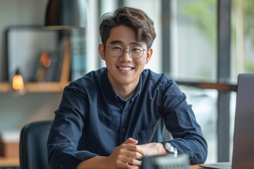 Wall Mural - Portrait of confident smiling Asian man sitting at desk