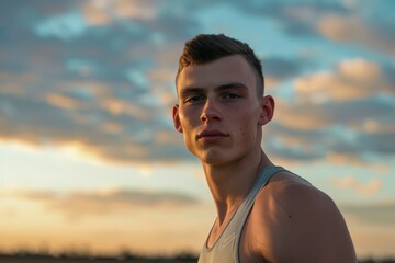 Confident young male athlete with sunset sky background